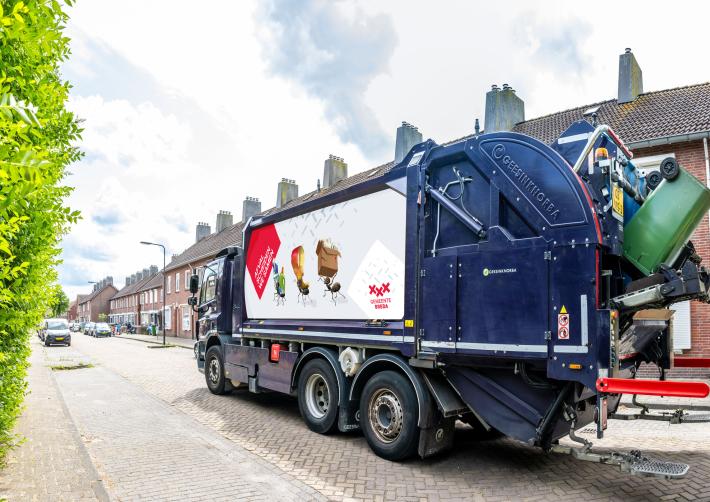Afval inzamelende vuilniswagen met op zijkant sticker 'Afval scheiden we samen'