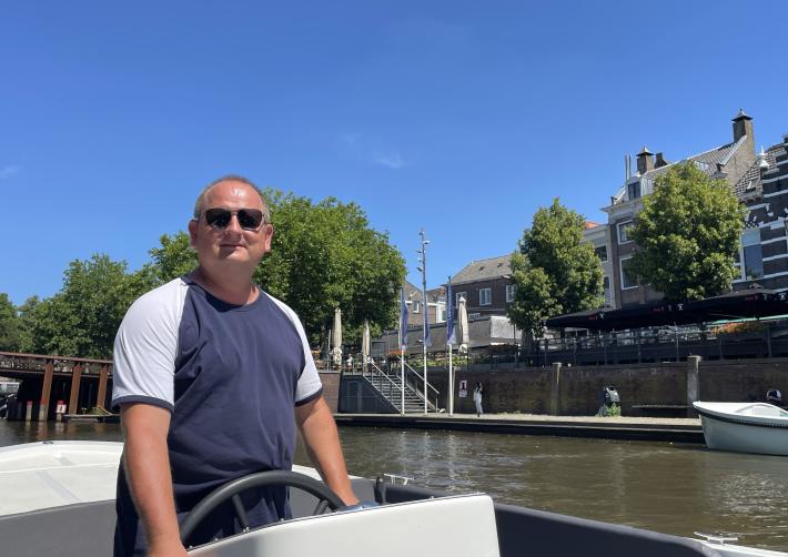 Johan staat achter het roer van een sloep van de rondvaart
