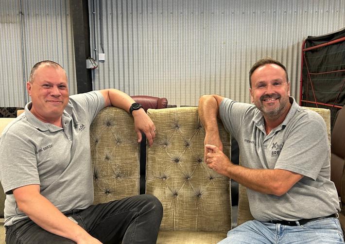 Melvin en Patrick zitten lachend naast elkaar op tweedehands stoelen
