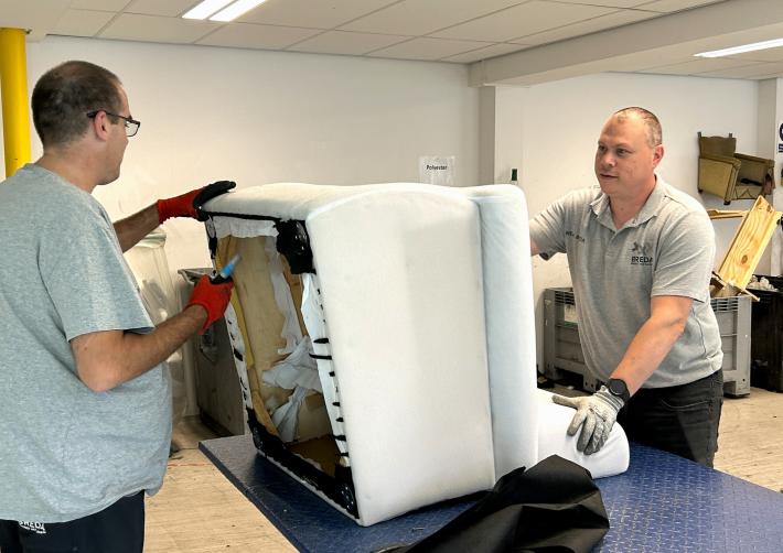 Melvin houdt een fauteuil vast terwijl een collega deze uit elkaar haalt