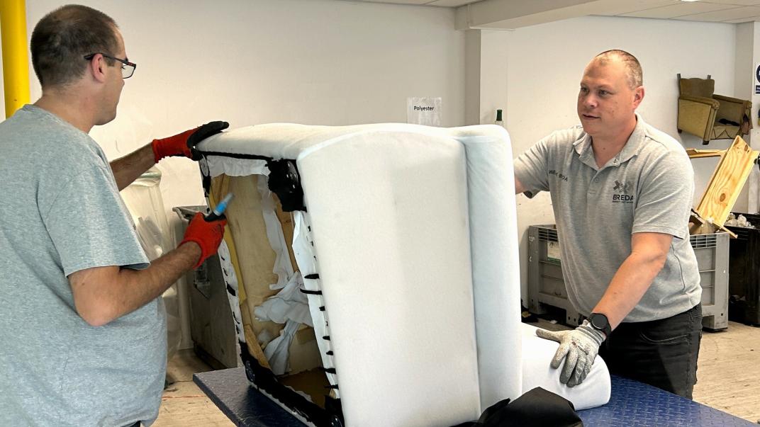 Melvin houdt een fauteuil vast terwijl een collega deze uit elkaar haalt